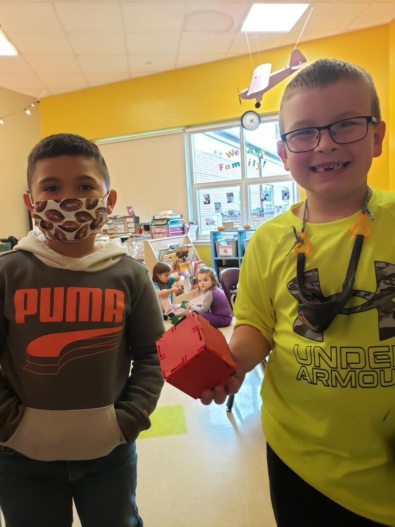 Two students in photo, one is holding a plastic block. 