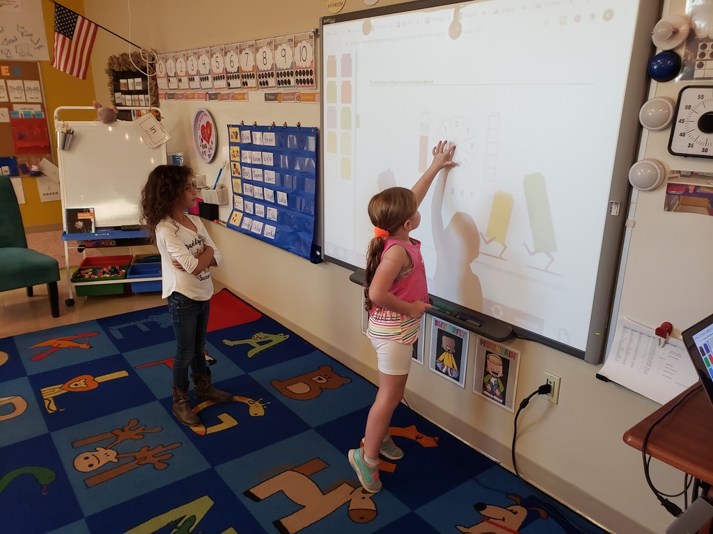 Two students are working on math on the smart board. 