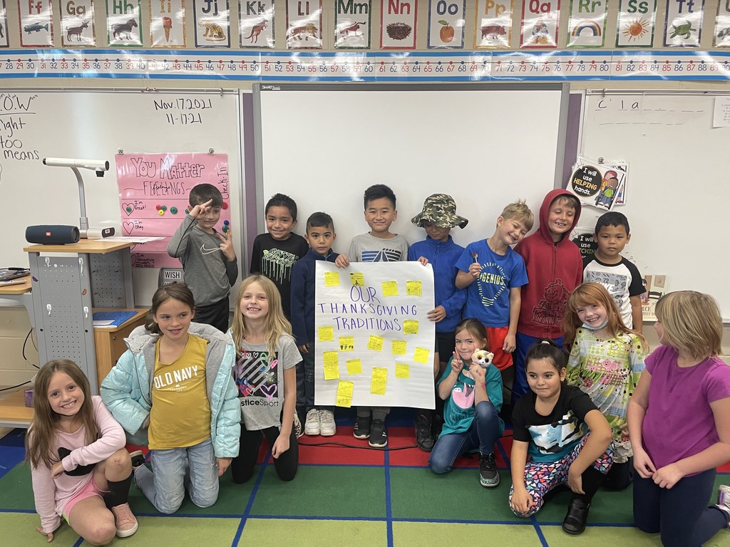 Class group photo, holding up their thanksgiving traditions. 