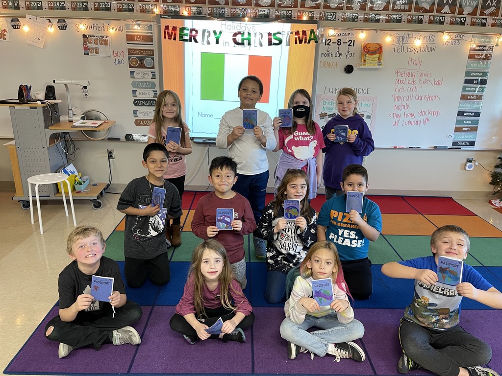 Students in class holding up their class project 'passports'. 