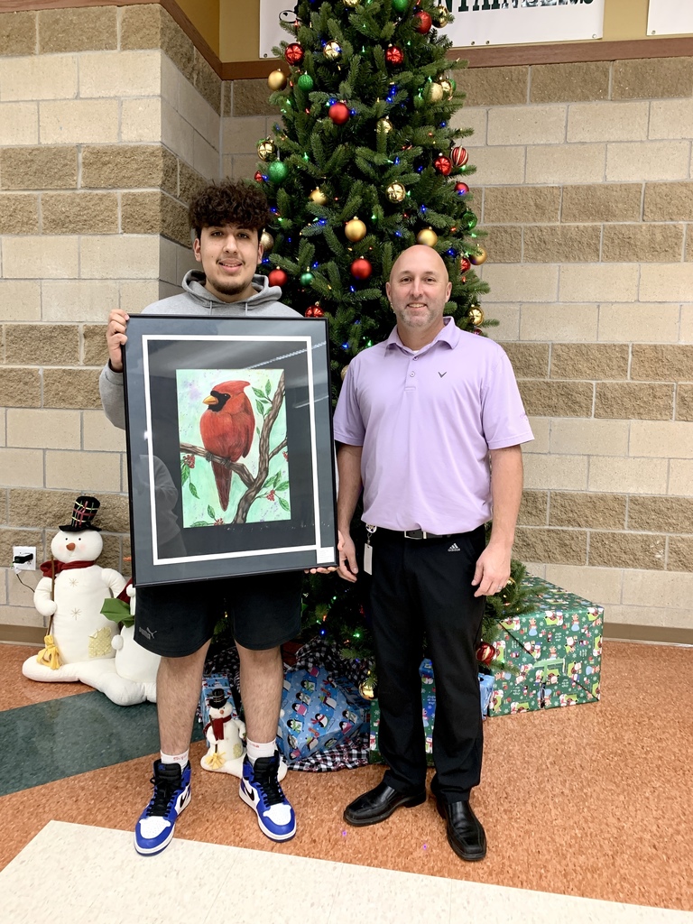Student and Dr. Drake standing in front of Christmas tree for art award. 