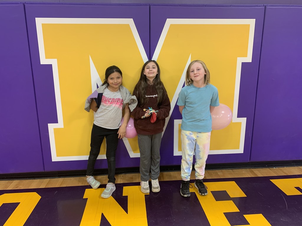 3 female students post for a photo holding their science project.