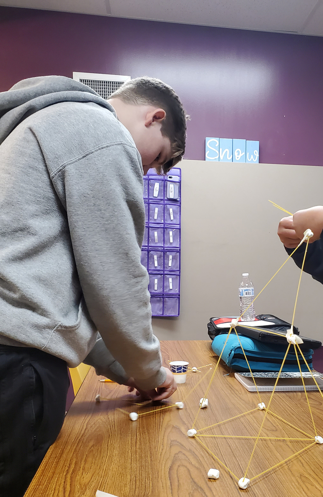 Student forming a design made of marshmallow and spaghetti. 