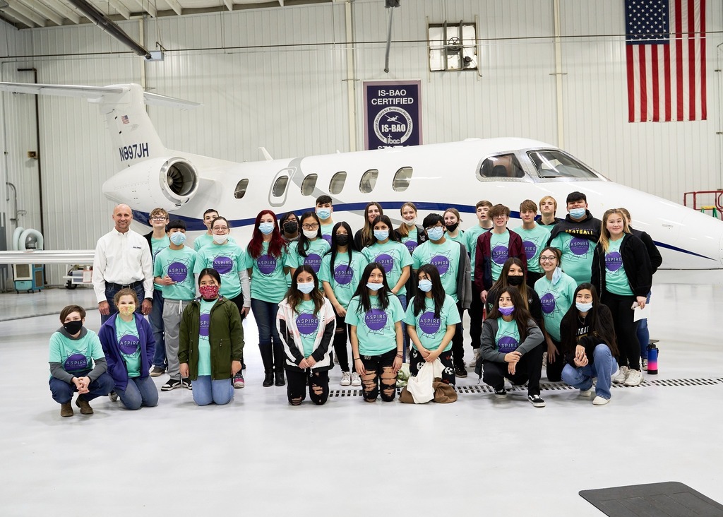 Group photo of students in the ASPIRE field trip, standing in front of a Jack Henry jet. 