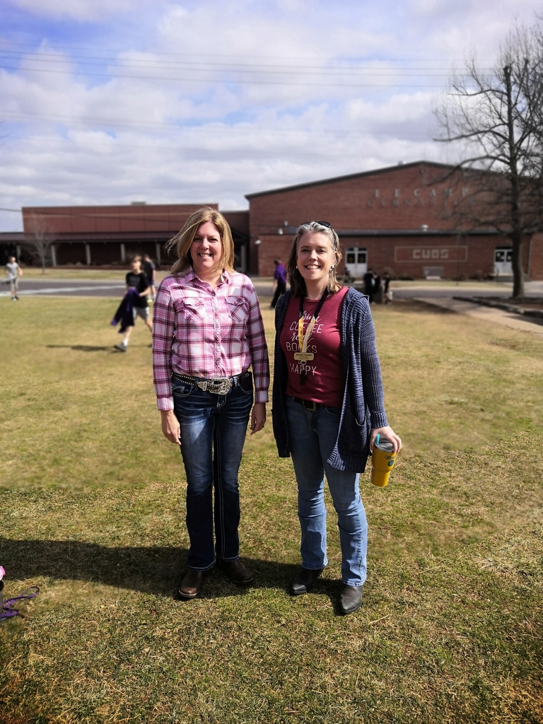 Two teachers standing outside posing for a photo together. 