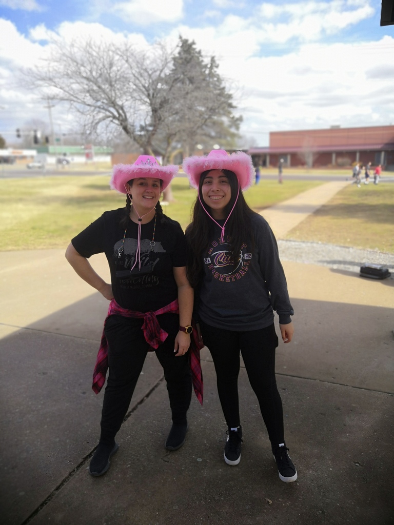 Teacher and student standing side by side with matching pink cowboy hats. 