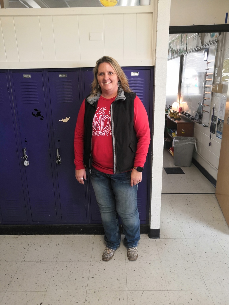 Teacher standing in front of  lockers with her cowboy wear. 