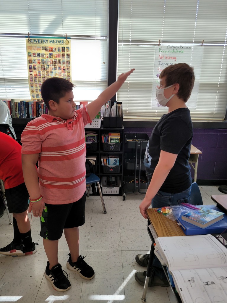 two boys work together to measure the angle of their shoulder. 
