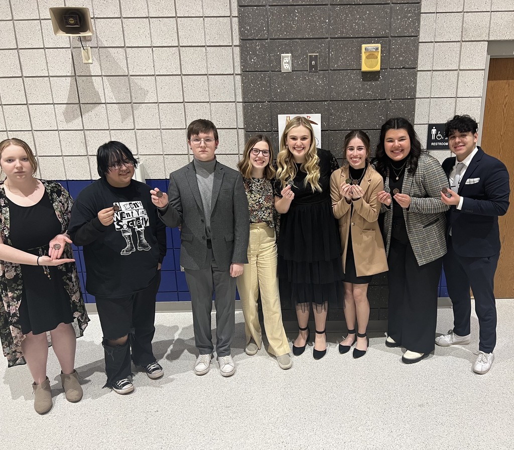 Students holding up medals from the Speech and Debate Tournament
