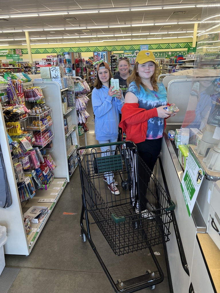 Two female students checking out at the cash register at Dollar Tree, cart in front. 