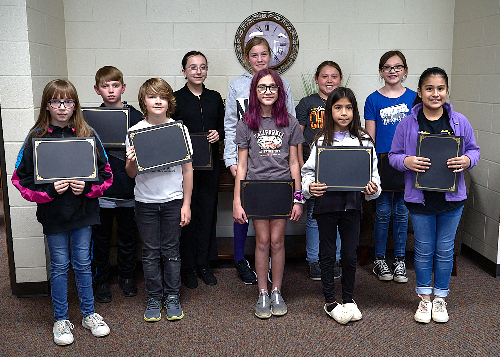 Children standing in two rows holding a certificate of achievement. 