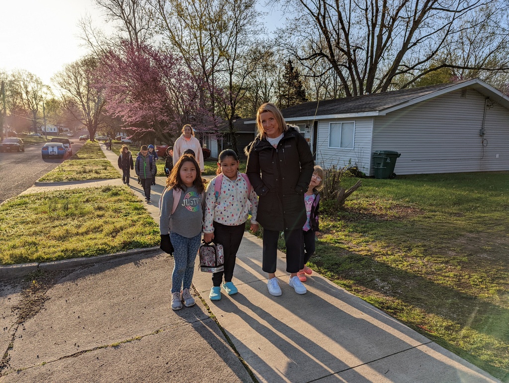 Two female students and one female teacher stop for a photo on the side walk on Walk to School Week.