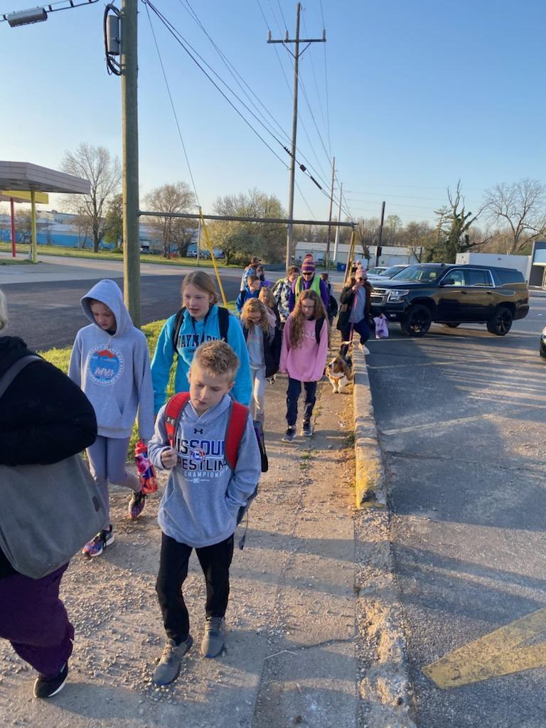 Group of students boys and girls walking on the side walk for Walk to School Week.