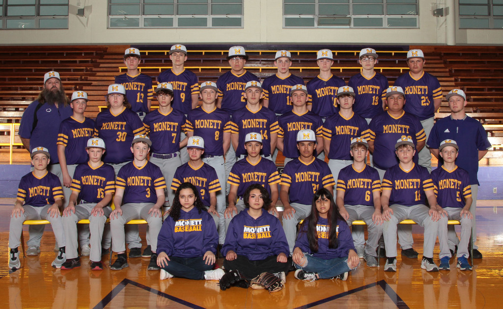 Boys baseball in purple uniforms taking a group sports photo. Managers are sitting in the front with purple sweaters. 