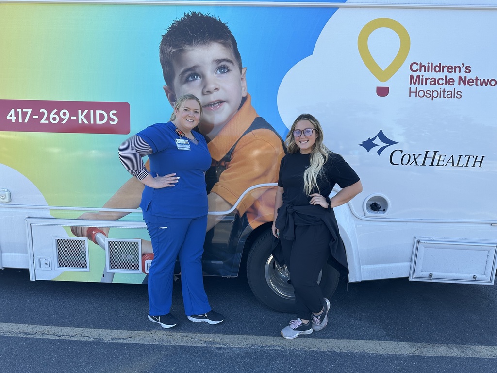 Nurses stand for photo in scrubs for photo in front of the CARE Mobile bus. 