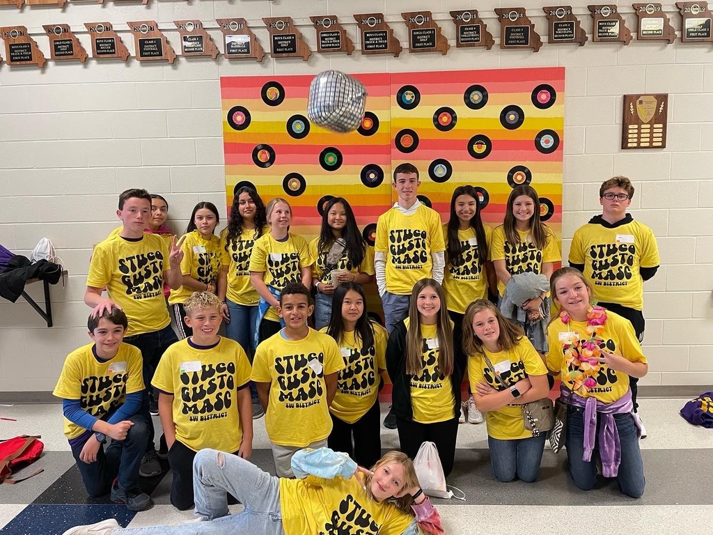STUCO Students sitting  and standing in rows for a photo. Students are all wearing their yellow STUCO shirts. 