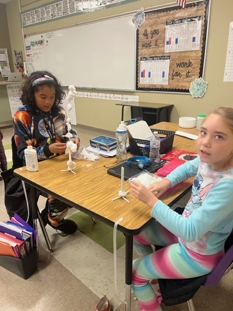 Students in class make a snowman out of cotton balls, cardboard, and glue. 