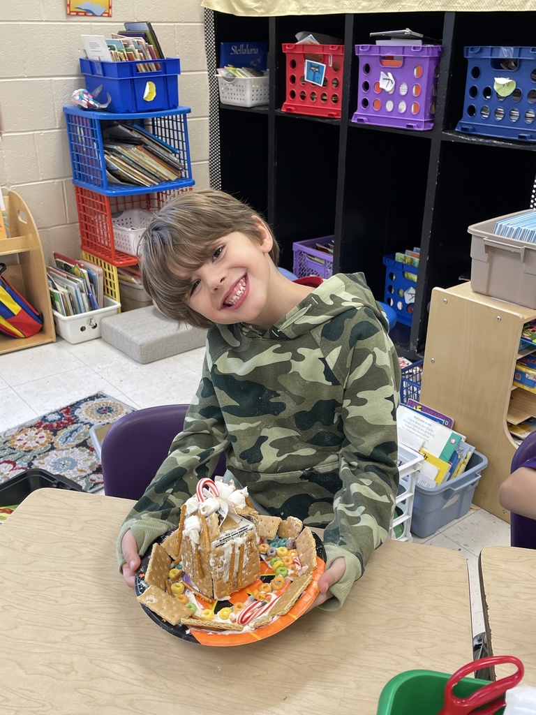 A boy holding a gingerbread house.