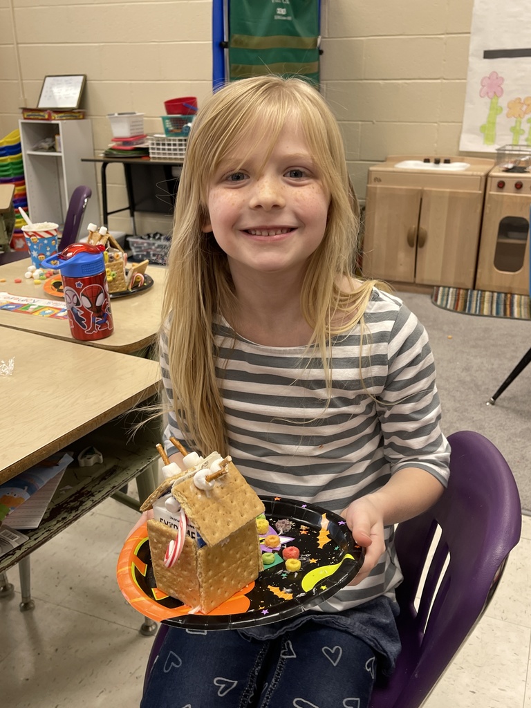 A girl holding a gingerbread house. 