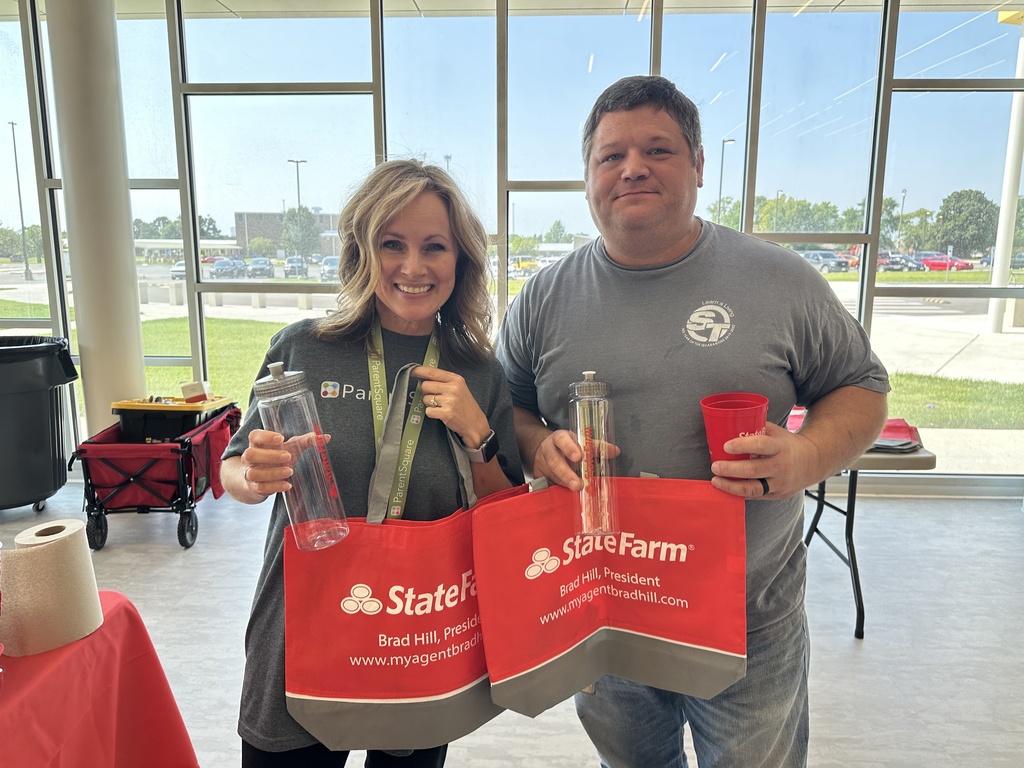 Male and female holding red bags and water bottles from State Farm