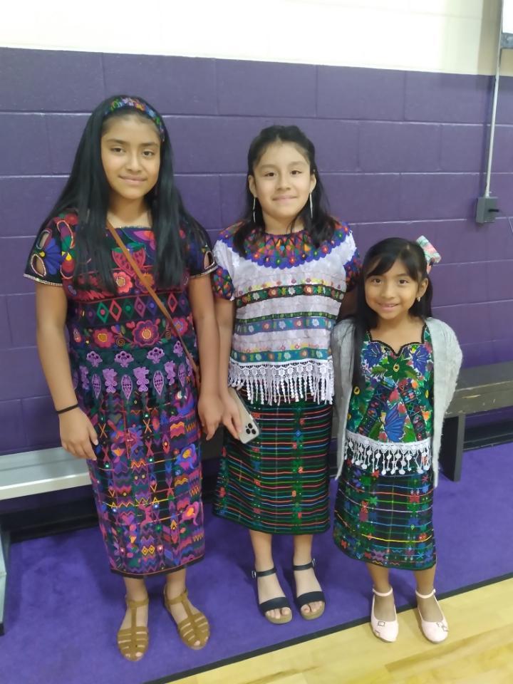 Three students stand next to each other in their Guatemalan attire. 